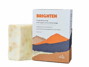 Σαπούνι BRIGHTEN σε χάρτινο κουτί με σχέδιο βουνών σε πορτοκαλί και βαθύ μπλε αποχρώσεις και απκ πίσω μία μπάρα σαπούνι με κίτρινες και πορτοκαλί αποχρώσεις